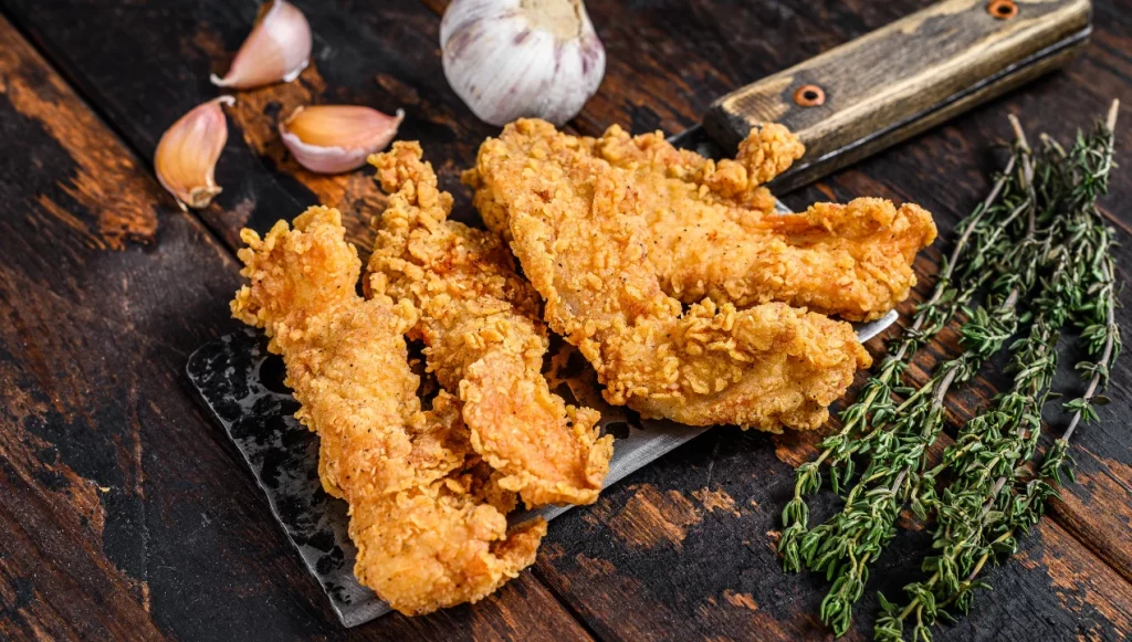 Pechugas de Pollo rebozado  con romero en tabla de cortar